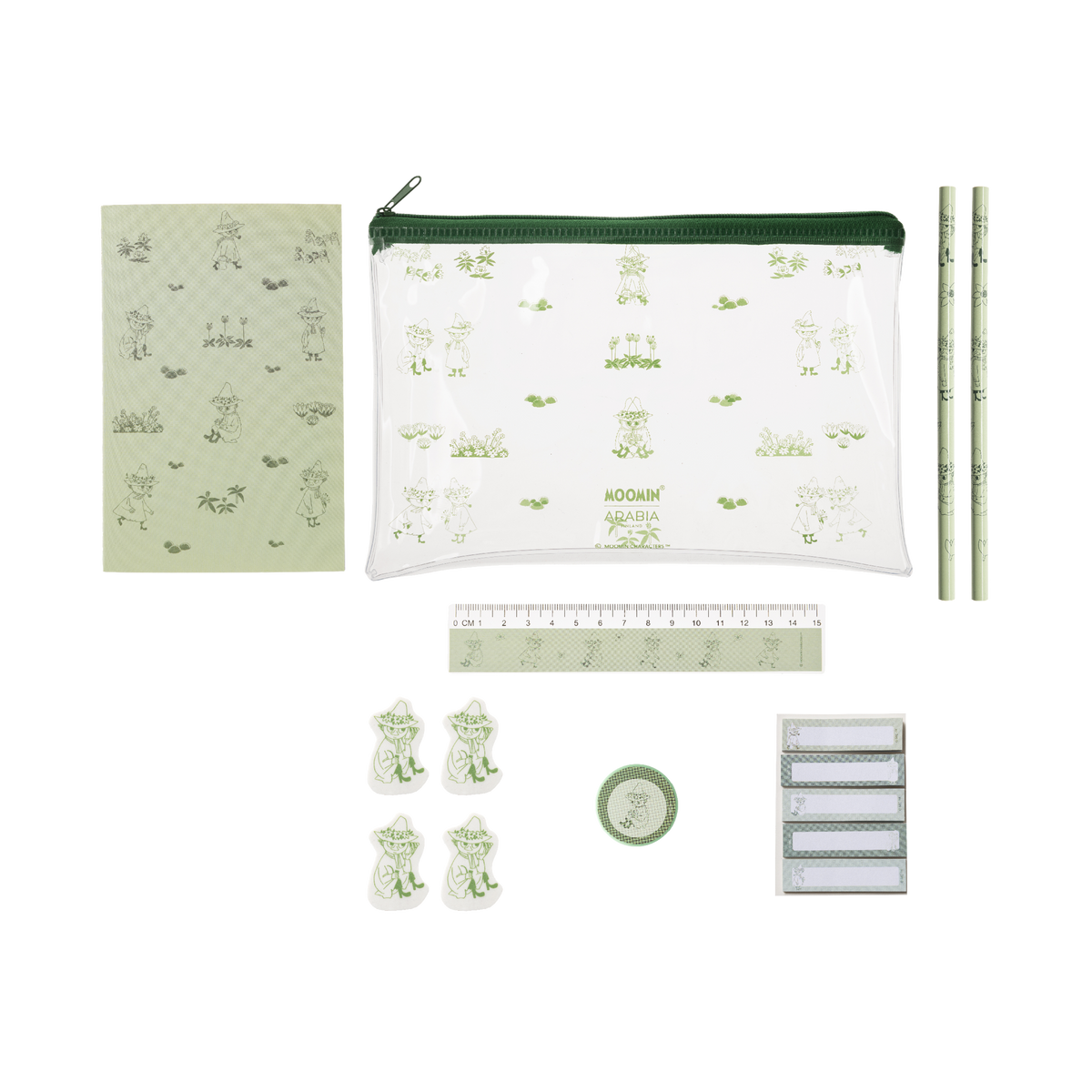 A stationery set laid out on a white background, including a clear zip pouch with a green zipper and pale green Snufkin illustrations, a matching notebook, two pencils, a ruler, four frog-shaped clips, a small round green item, and a stack of white labels. 
