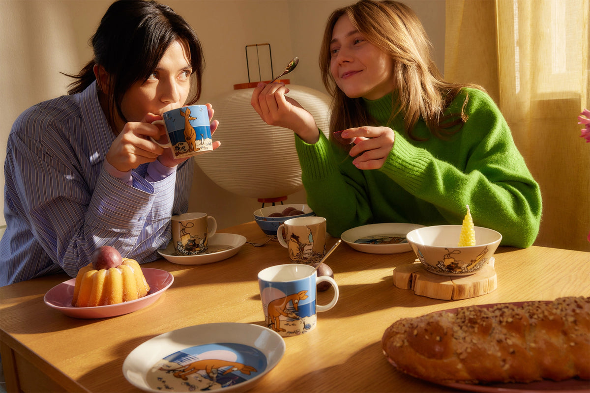 Two people enjoying a meal together at a table with dishes of Sniff and Muskrat design.