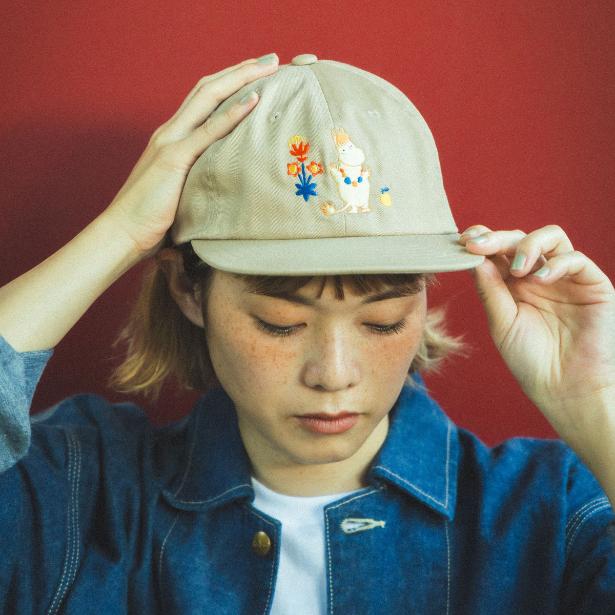 Mumin keps beige Beams - Person wearing a beige cap with Snorkmaiden design against a red background