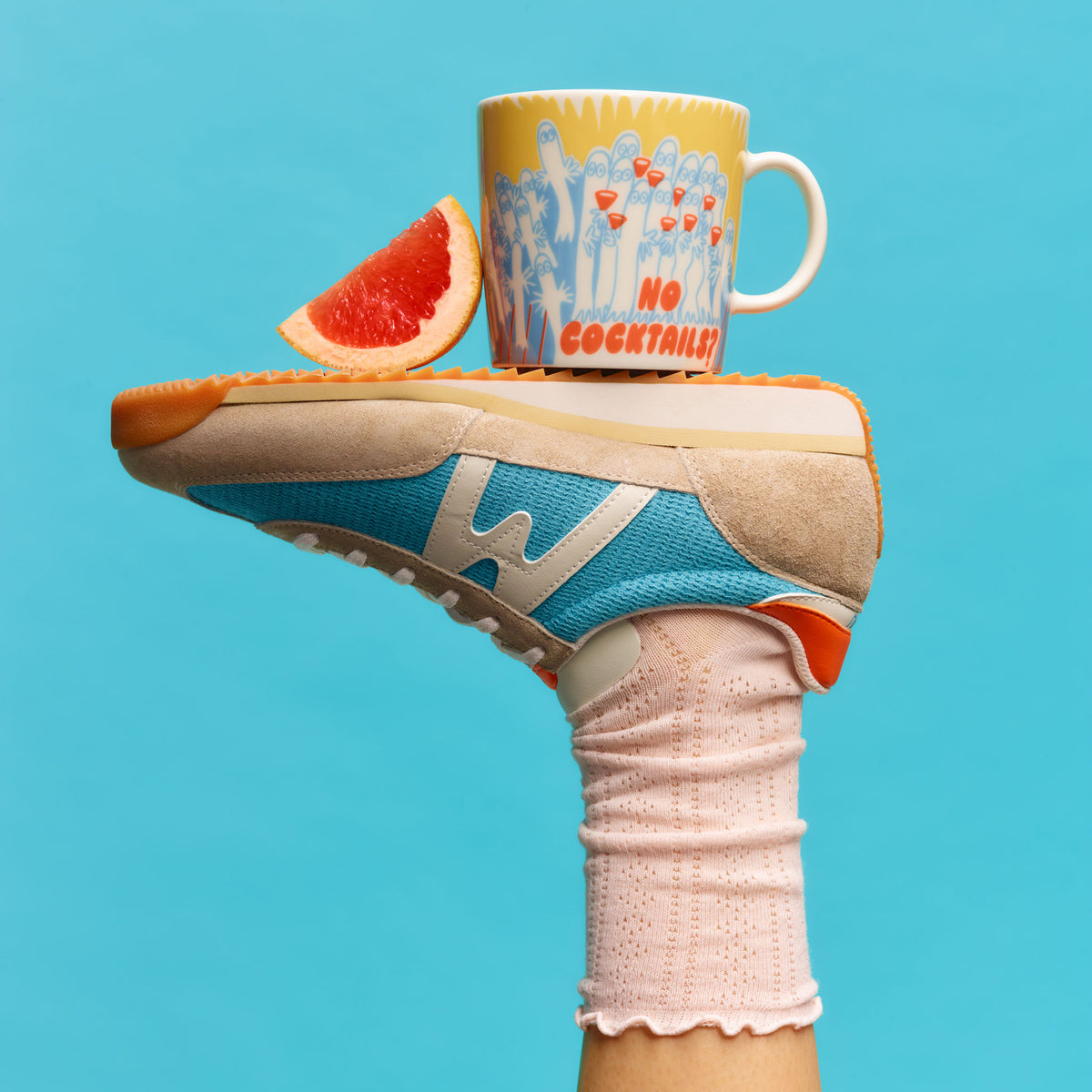 Sneaker with a Party Queue mug and grapefruit slice on a blue background