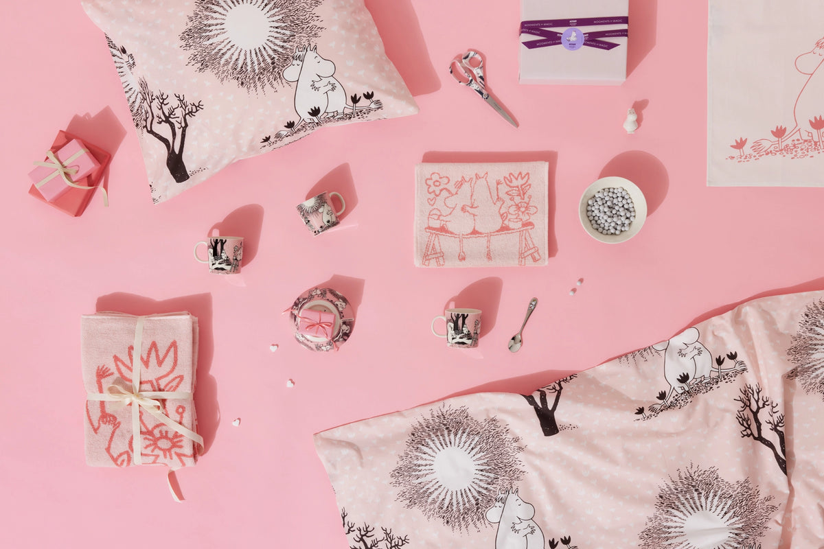 Decorative Moomin Love pillows and items on a pink background