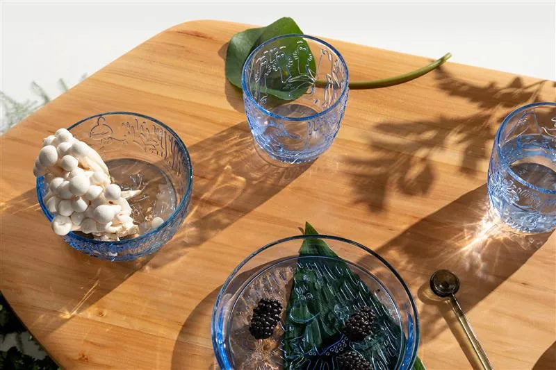 Three blue glass bowls with decorative elements on a wooden surface