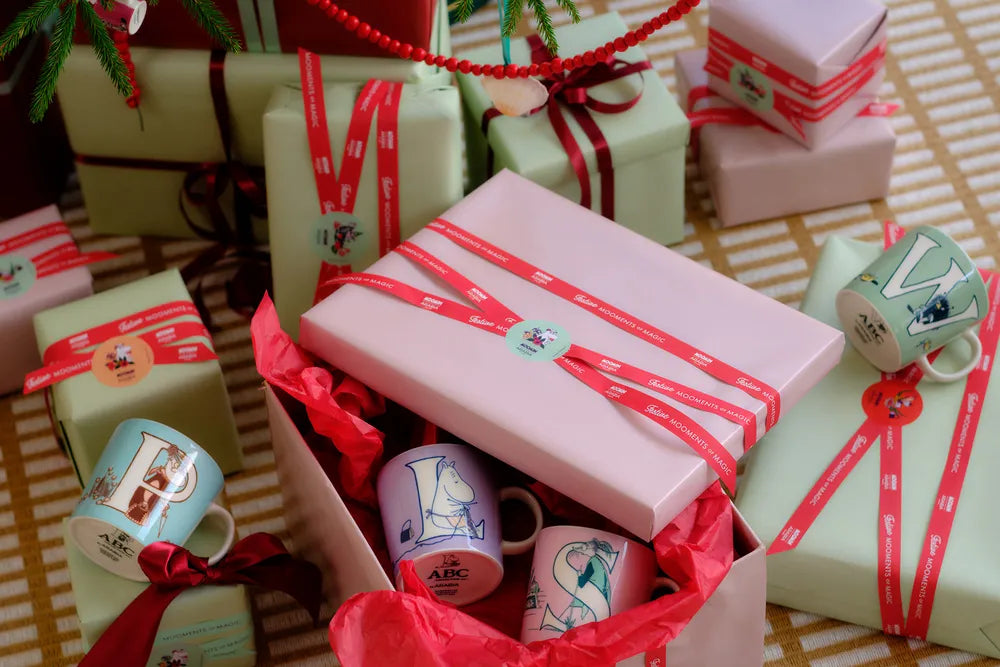 Gift boxes with ribbons and alphabet mugs on a patterned rug